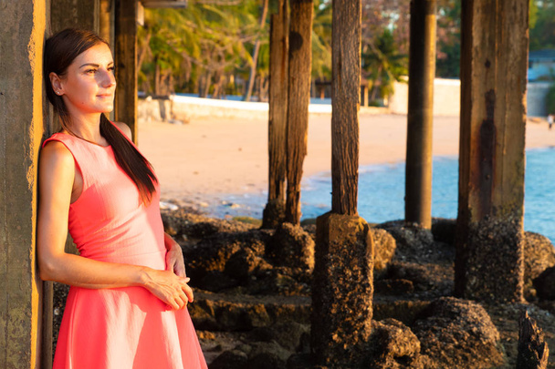 Nainen seisoo rannalla iltaisin. Tyttö auringonlaskun aikaan. Viehättävä nuori nainen nauttimassa auringon viimeisistä säteistä. kopioi tilaa tekstille
 - Valokuva, kuva