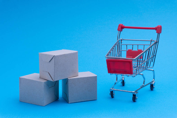 Carrinho de compras e caixa em fundo azul, negócio e conceito de compras. Foco seletivo
 - Foto, Imagem