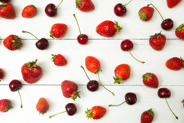 Ripe red strawberry and cherry on a white table, top view. - Foto, Bild