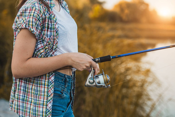 Cute woman is fishing with rod on the summer lake - Фото, зображення