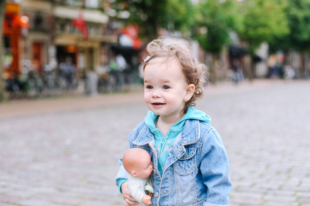 Bouclé bébé fille en jeans vêtements de marche dans la ville
 - Photo, image