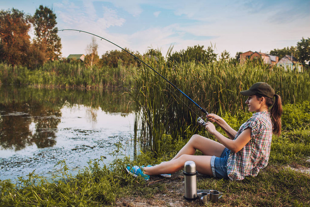 Happy woman is fishing with rod on the summer lake - Fotoğraf, Görsel