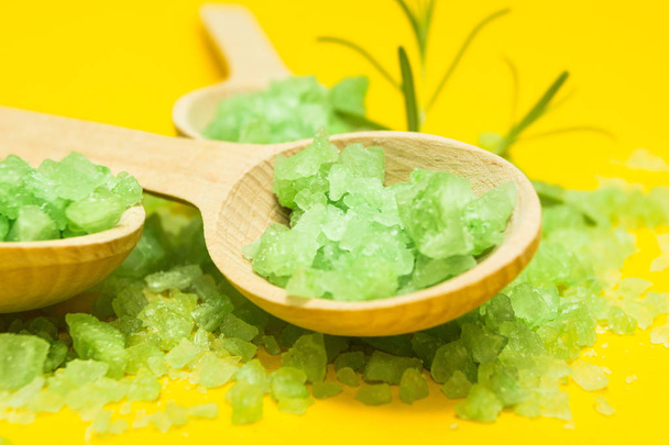 Green Salt in three wooden spoons on a yellow background. Vegetable ingredients for skin care. - Foto, imagen