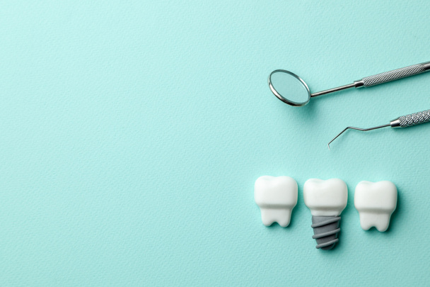 Dentes brancos saudáveis e implantes em fundo de hortelã verde e ferramentas de dentista espelho, gancho. Espaço de cópia para texto
. - Foto, Imagem
