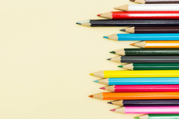 Multicolored pencils on a pastel yellow background, space for text. - Fotoğraf, Görsel
