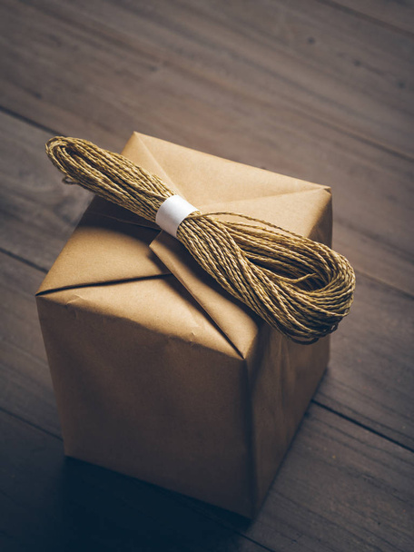 brown cube box with a bundle of string on, isolated on wooden table. - Foto, Imagem