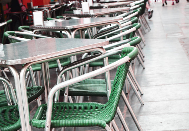 Open empty street cafe, tables and chairs with metal frame and wicker furniture, selective focus and close-up. - Photo, Image