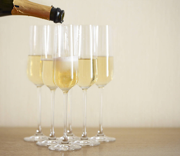 Wlewanie szampan z butelki do sześciu przezroczyste okulary na tle światła - Zdjęcie, obraz