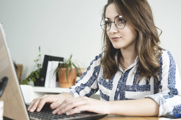 Молодая деловая женщина работает на ноутбуке в офисе
. - Фото, изображение