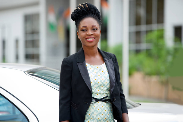 Confident and smiling businesswoman in black suit standing outdoors (day) - Fotó, kép