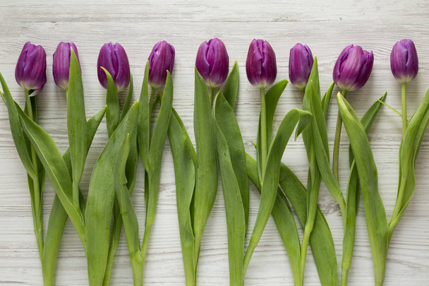 Purple tulips on white wooden surface, top view. Flat lay, overhead, from above.  - Foto, Bild