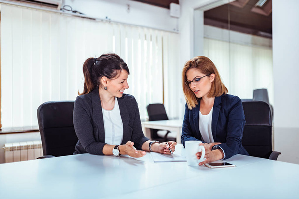 Two beautiful business women talking at conference room. - 写真・画像