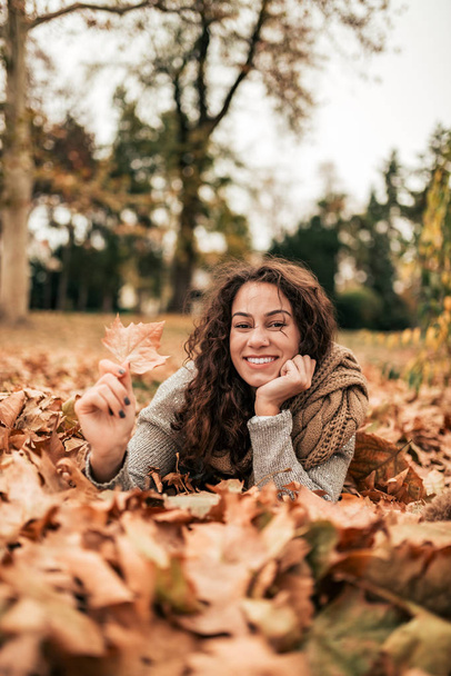Young woman relaxing autumn park, looking at camera. - Foto, afbeelding