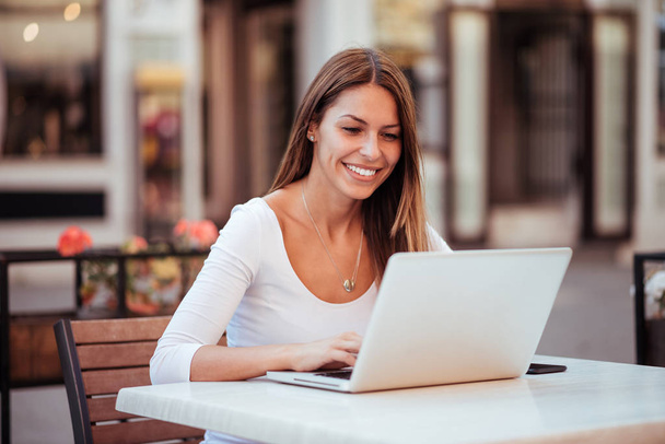 Attractive young woman using laptop in the cafe outdoors. - Foto, Imagen