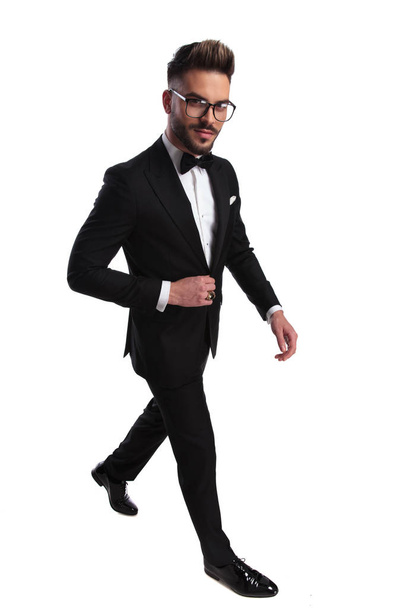 uomo elegante che cammina mentre organizza la giacca con un leggero sorriso sul viso
 - Foto, immagini