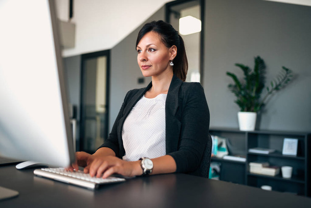 Portrait of beautiful businesswoman working on computer in modern office.  - Photo, image
