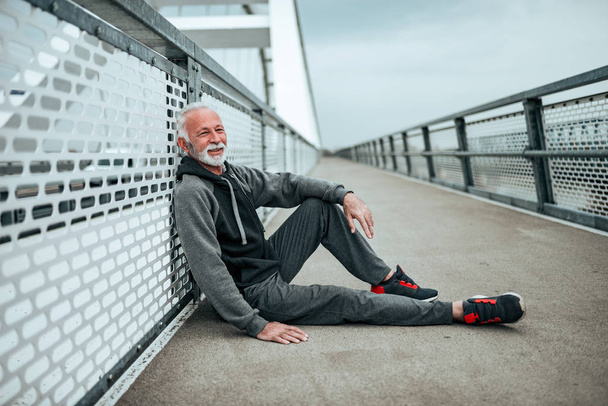 Senior athlete sitting on the city bridge. - Foto, immagini