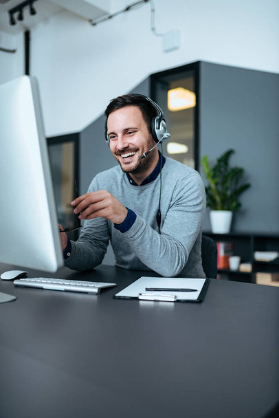 Casual smiling businessman with headset at work in modern office. Copy space. - Foto, Bild