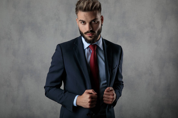 serious businessman holding his suit's collar and looks at the camera  - Foto, immagini