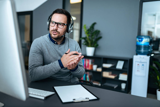 Attractive male support center agent with headset on talking to client. - Fotografie, Obrázek