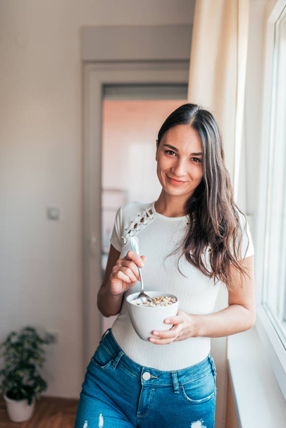 Healthy young woman holding a bowl of cereal. Looking at camera. - Fotografie, Obrázek