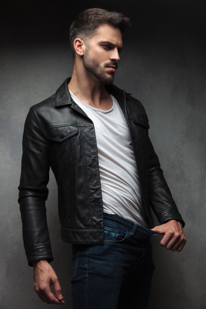 сексуальна людина в шкіряній куртці показує, скільки ваги він втратив, витягнувши штани пальцем в студії
 - Фото, зображення