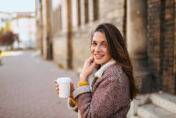 Młoda kobieta na ulicy picia kawy. - Zdjęcie, obraz