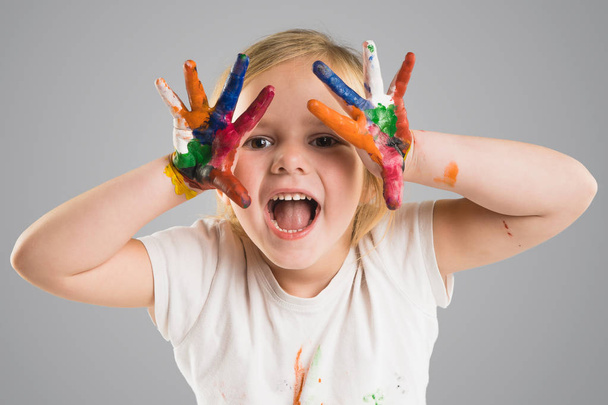beautiful little girl with hands in the paint on the gray background - Photo, Image