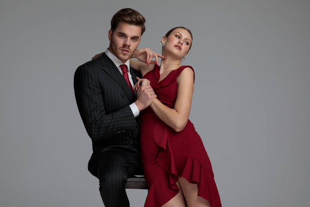 elegant young couple in a sexy pose, on grey studio background - 写真・画像