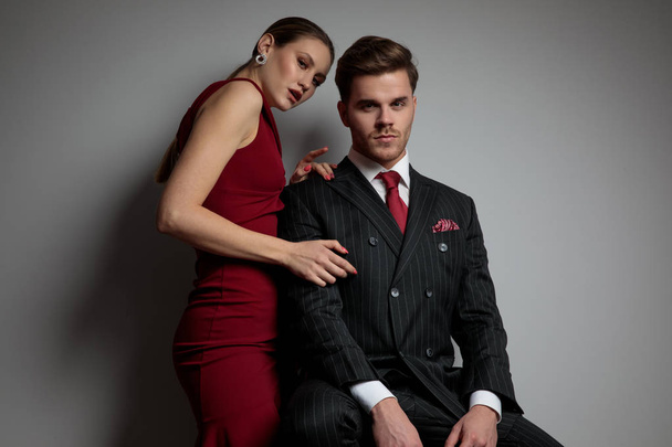elegant woman rests her hands on her man's shoulder on grey background - Photo, Image