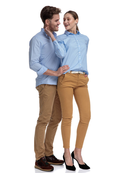 embraced casual man and woman looking at each other while standing on white background - Foto, afbeelding