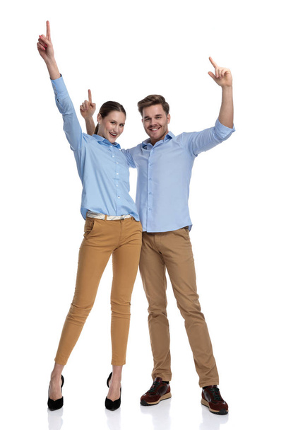 счастливая случайная пара празднует успех с руками в воздухе на белом фоне
 - Фото, изображение