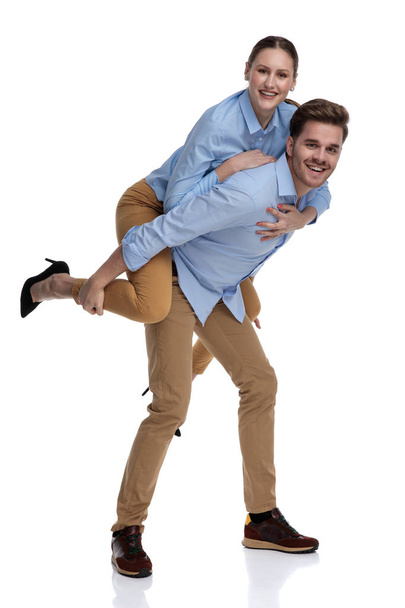 happy casual man carries woman on his back on white background - Photo, image