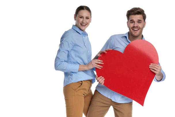 laughing young couple sharing a big red heart on white background - Fotografie, Obrázek