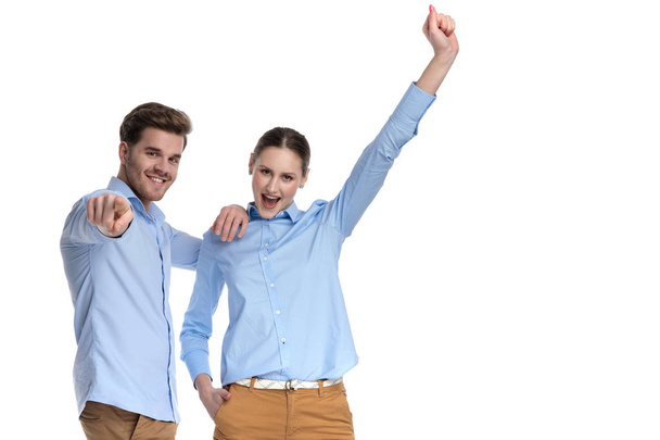 glückliches junges Paar wählt einen Gewinner, während es auf weißem Hintergrund steht - Foto, Bild