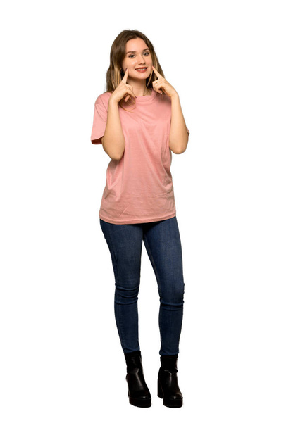 Täyspitkä kuva teini-ikäisestä tytöstä, jolla on vaaleanpunainen pusero hymyilevä iloinen ja miellyttävä ilme eristetyllä valkoisella taustalla
 - Valokuva, kuva