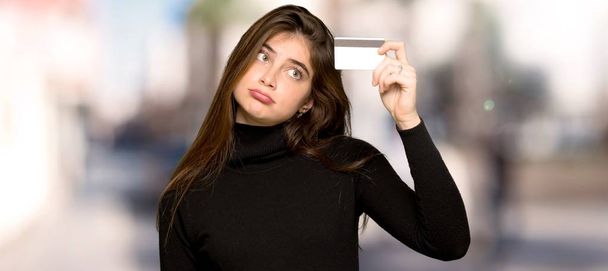 Chica bonita tomando una tarjeta de crédito sin dinero al aire libre
 - Foto, Imagen