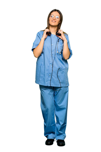 Full body of Young nurse listening to music with headphones - 写真・画像