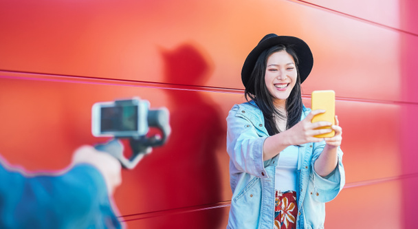 Aziatische mode vrouw vlogging en het gebruik van mobiele smartphone outdoor - Happy Chinese trendy meisje, plezier in het maken van video met gimbal camera - Millennials mensen, generatie z en technologie concept - Foto, afbeelding