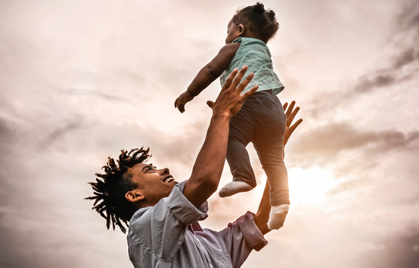 Père heureux jouant avec sa petite fille pendant le coucher du soleil - Afro famille s'amuser en plein air - Concept d'enfant, bonheur et parentalité
 - Photo, image