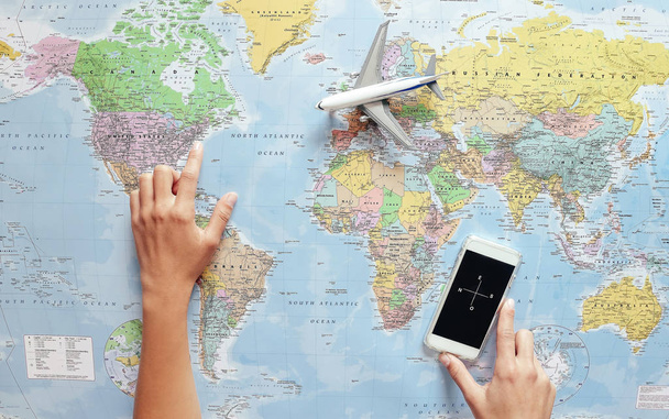 Draufsicht einer jungen Touristin, die ihr nächstes Reiseziel mit Weltkarte und Handy-Kompass-App zeigt - Konzept für Abenteuer, Technologie, Tourismus und Lebensstil der Reisenden - Foto, Bild