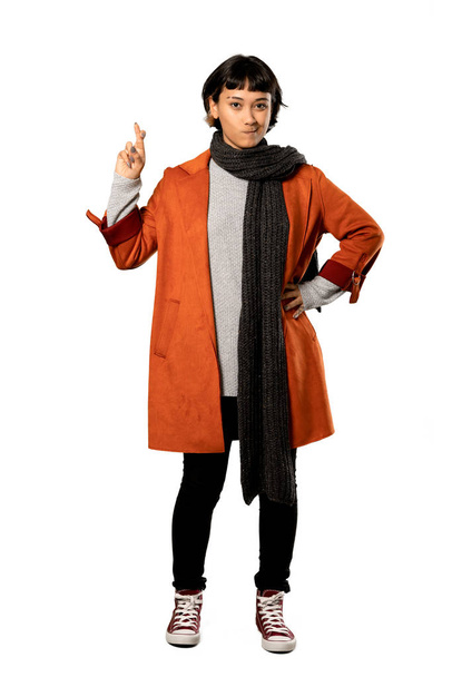 Una foto completa de una mujer de pelo corto con abrigo con dedos cruzando y deseando lo mejor sobre un fondo blanco aislado
 - Foto, Imagen