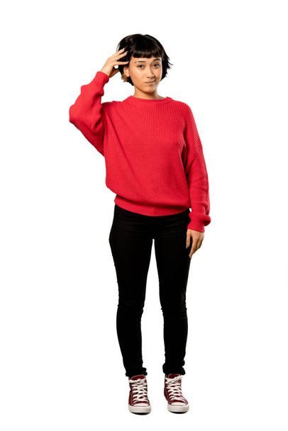 Una foto completa de una chica de pelo corto con suéter rojo con una expresión de frustración y no comprensión sobre un fondo blanco aislado
 - Foto, imagen