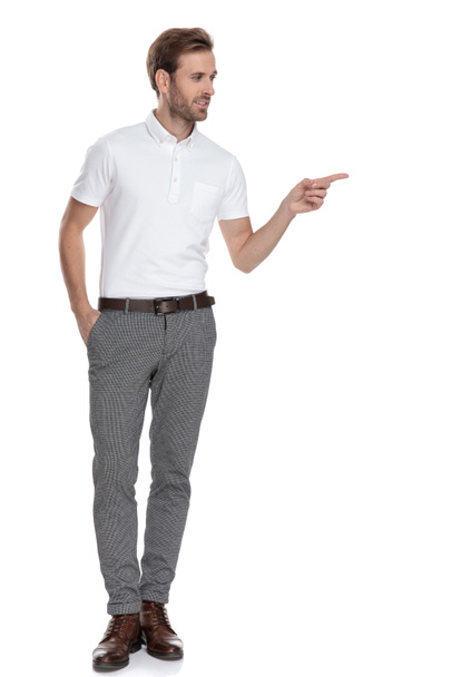 imagem de corpo inteiro de um homem casual inteligente apontando o dedo para o lado, recomendando algo, no fundo branco
 - Foto, Imagem