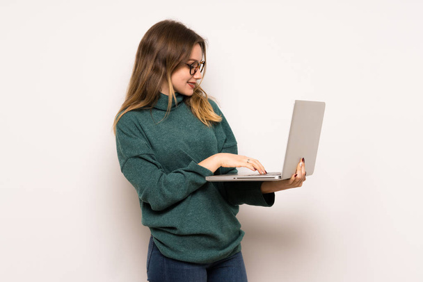 Дівчина-підліток над білою стіною з ноутбуком
 - Фото, зображення