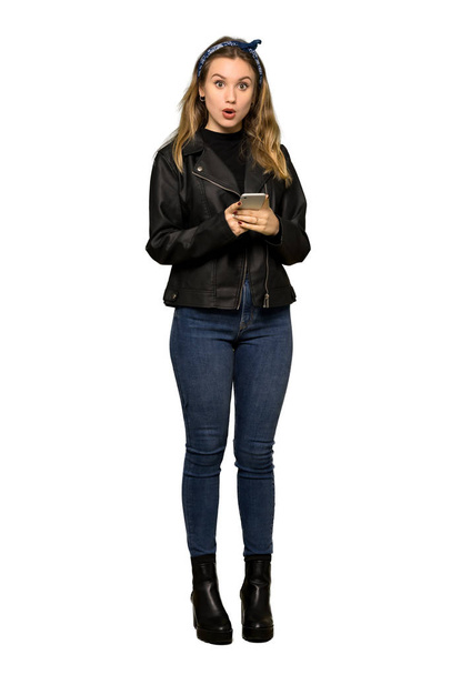 Celovečerní snímek dospívající dívky s koženou bundu odesláním zprávy s mobilním telefonem na izolované bílém pozadí - Fotografie, Obrázek