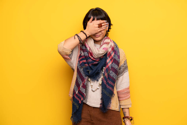 Young hippie woman over yellow wall covering eyes by hands. Do not want to see something - Photo, Image