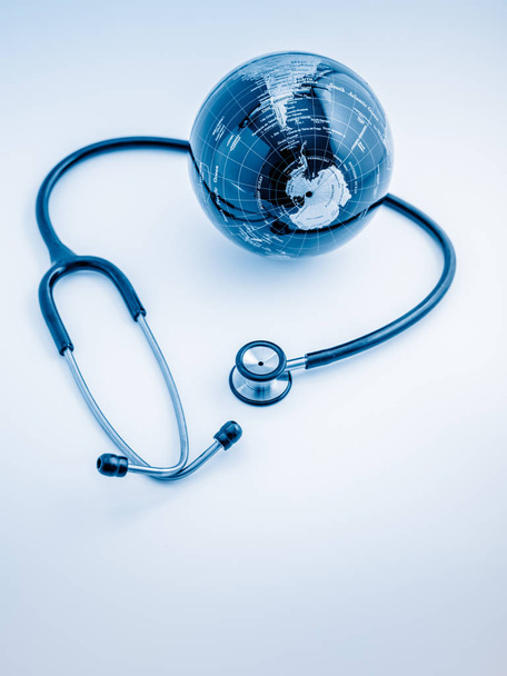 Wereldwijde gezondheidszorg. Globe en stethoscoop, studio shot.blue getinte beelden. - Foto, afbeelding