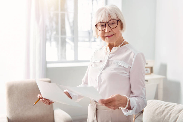 Smiling elderly woman studying documents with research results - Foto, Bild