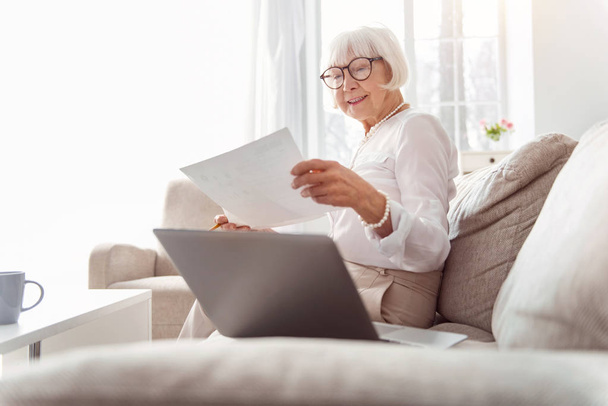 Pleasant elderly woman studying research data - Fotó, kép